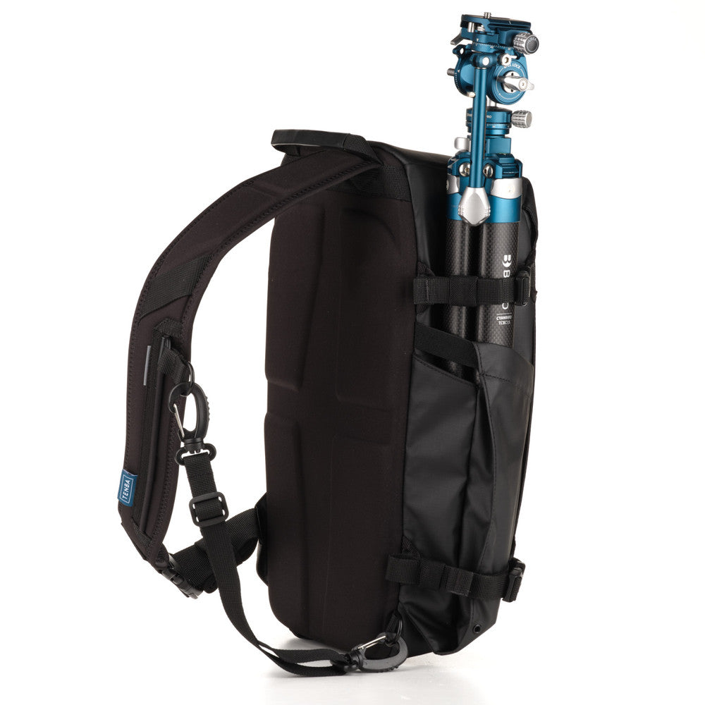 Black backpack with a camera tripod attached on a white background