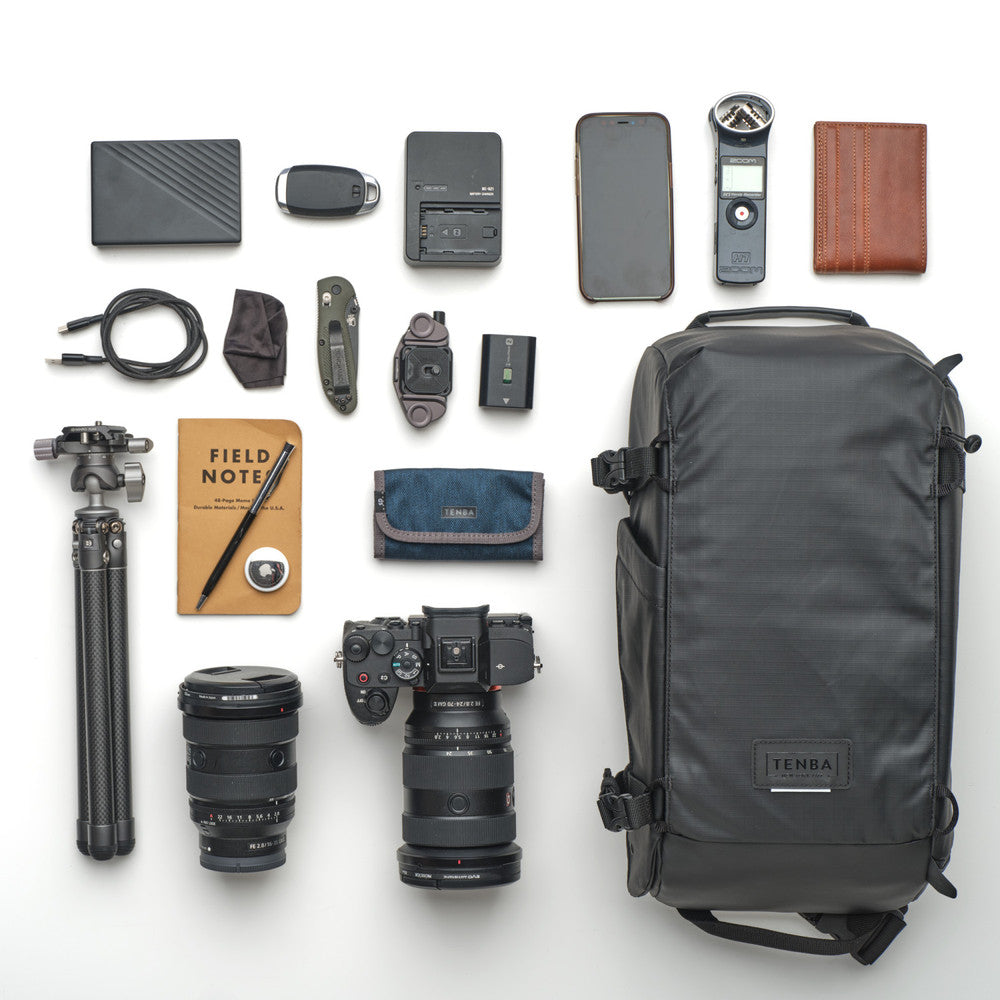 Collection of photography equipment including a backpack, camera, lenses, and accessories on a white background.