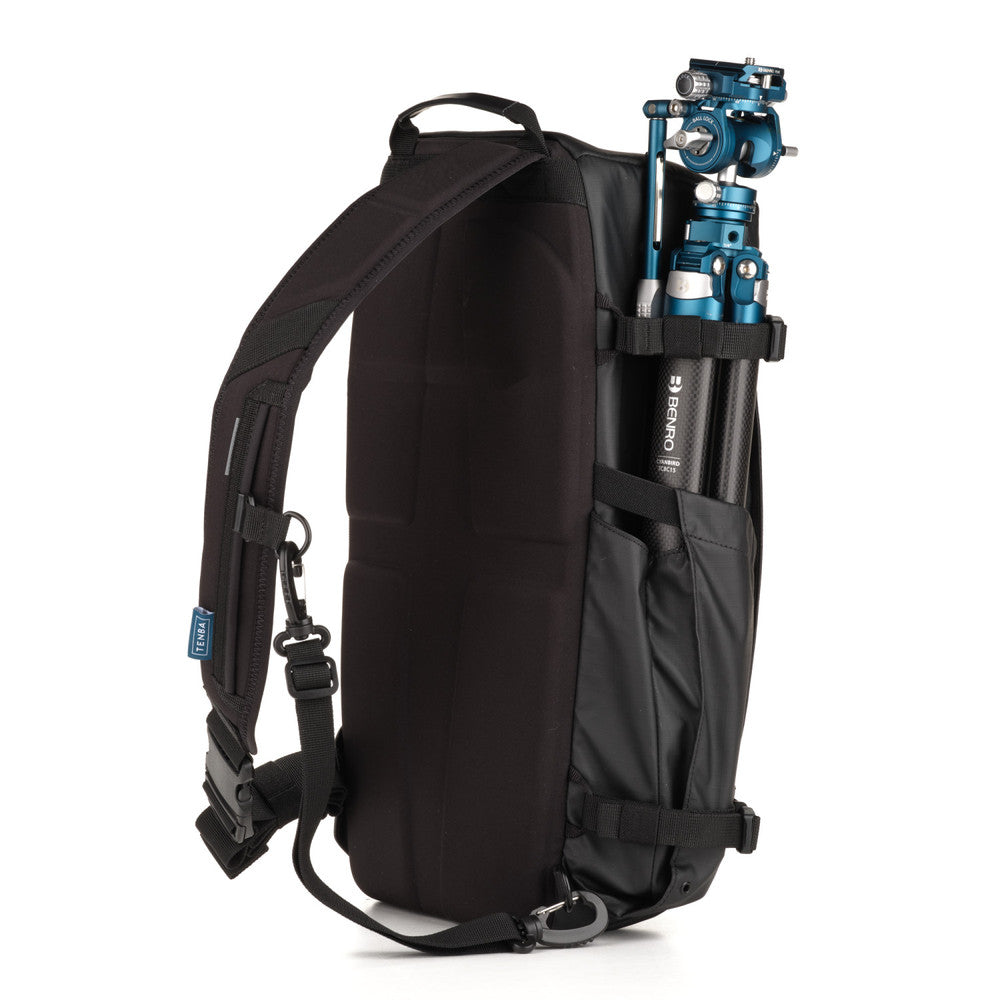 Black backpack with a camera tripod inside on a white background