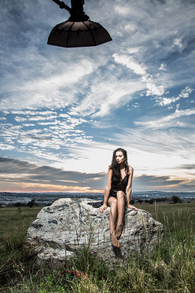 Model sitting on a rock, lit up using the B1 with the sunrise in the background