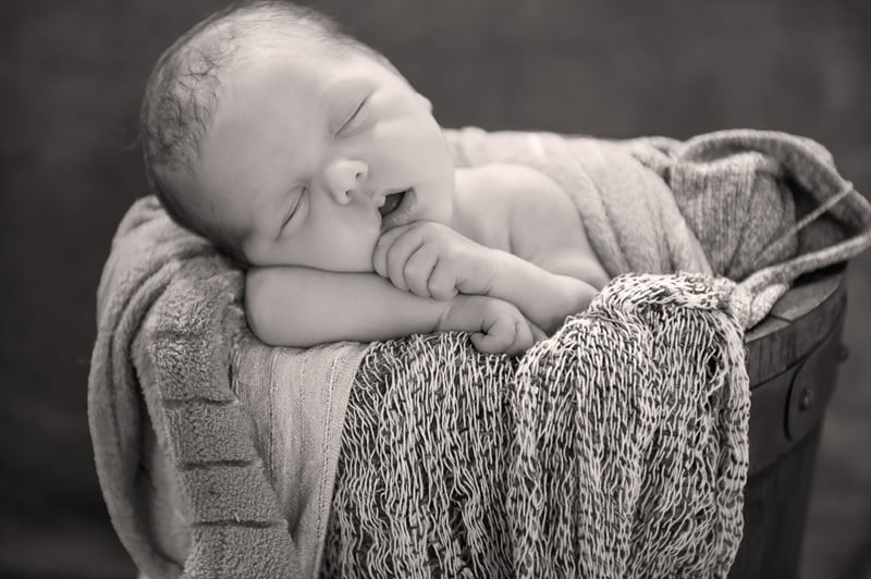 Baby posed sleeping sweetly in a basket filled with blankets