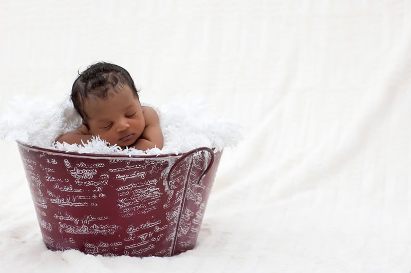 Baby posed sleeping in a bucket filled with blankets