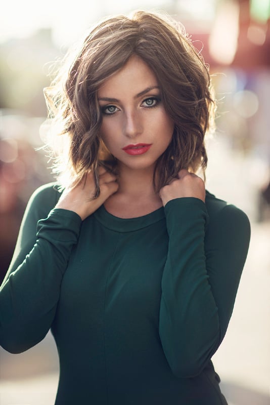Girl with brown hair and red lips standing in the street