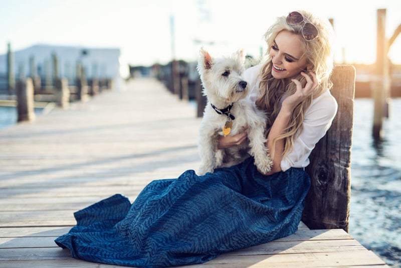 Photo of a model sitting on a deck with a dog