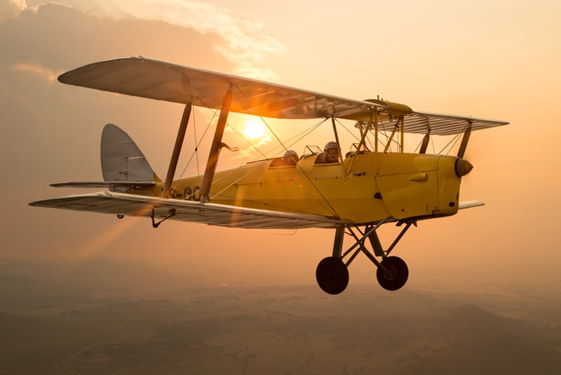 Photograph of an aircraft flying with the sun setting behind it