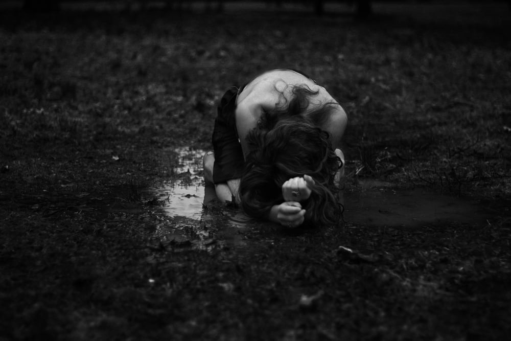 A black and white self portrait by Alison where she's kneeling in mud