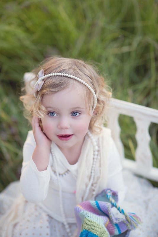 Toddler Photography: Little girl sitting on a small chair in long green grass