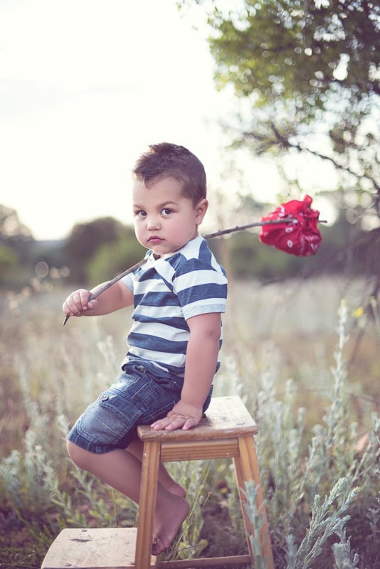 Toddler Photography: Little boy sitting on a stepping-stool holding a bindle.