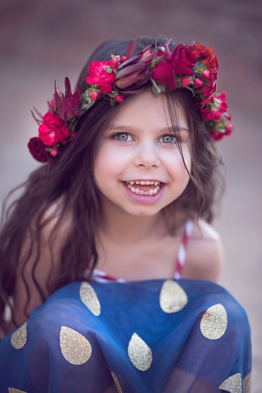 Toddler Photography: A little girl with a crown of deep red flowers on her long dark hair