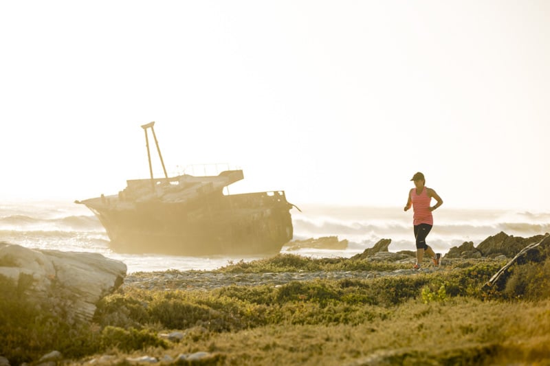 Racer running on the beach with a big ship wreck in the background