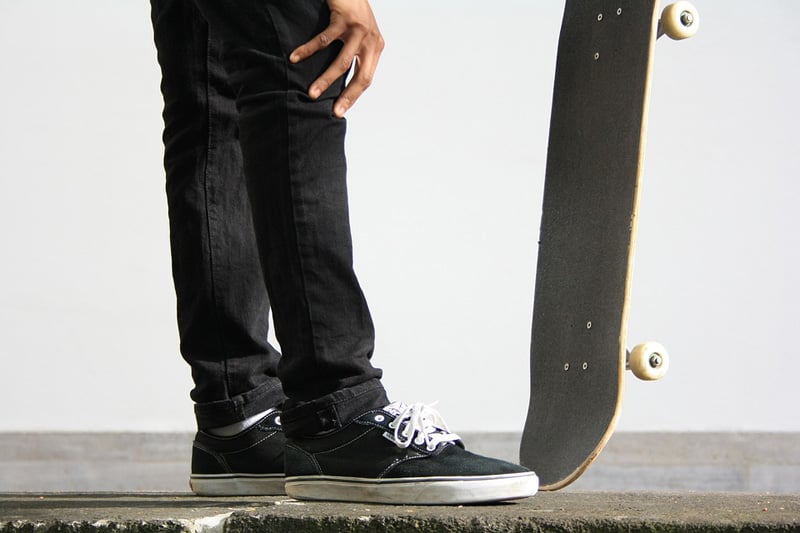 A photograph of a guy and his skateboard taken from a low angle