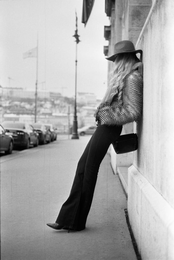 Black and white film photograph of stylish woman leaning against a wall by Matthew Osborne