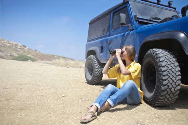 Girls sitting next to jeep with binoculars 