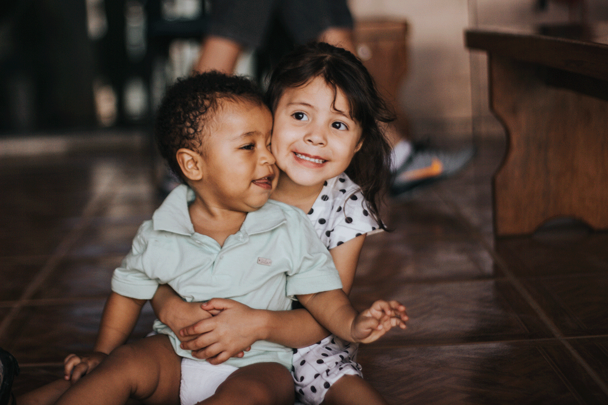 A siblings portrait where sister holds younger brother. Image by Chayene Rafaela.