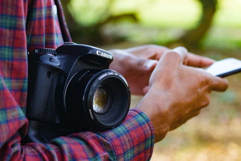 Man holding a camera and a mobile phone Man holding a camera and a mobile phone