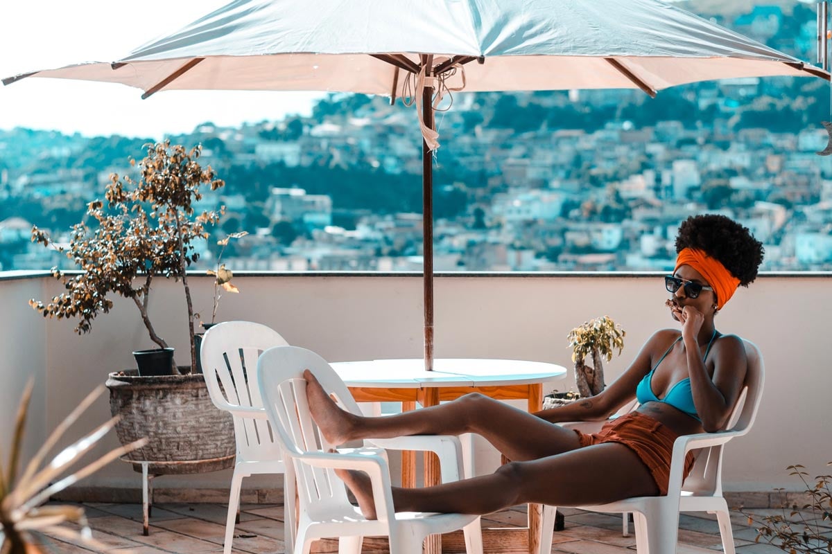Sunny summer days Woman sitting under an umbrella on a balcony on a hot summer day