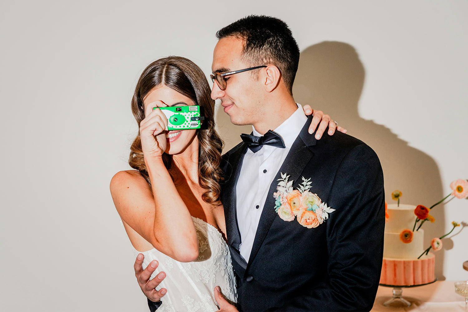 Wedding couple posing with a film camera.