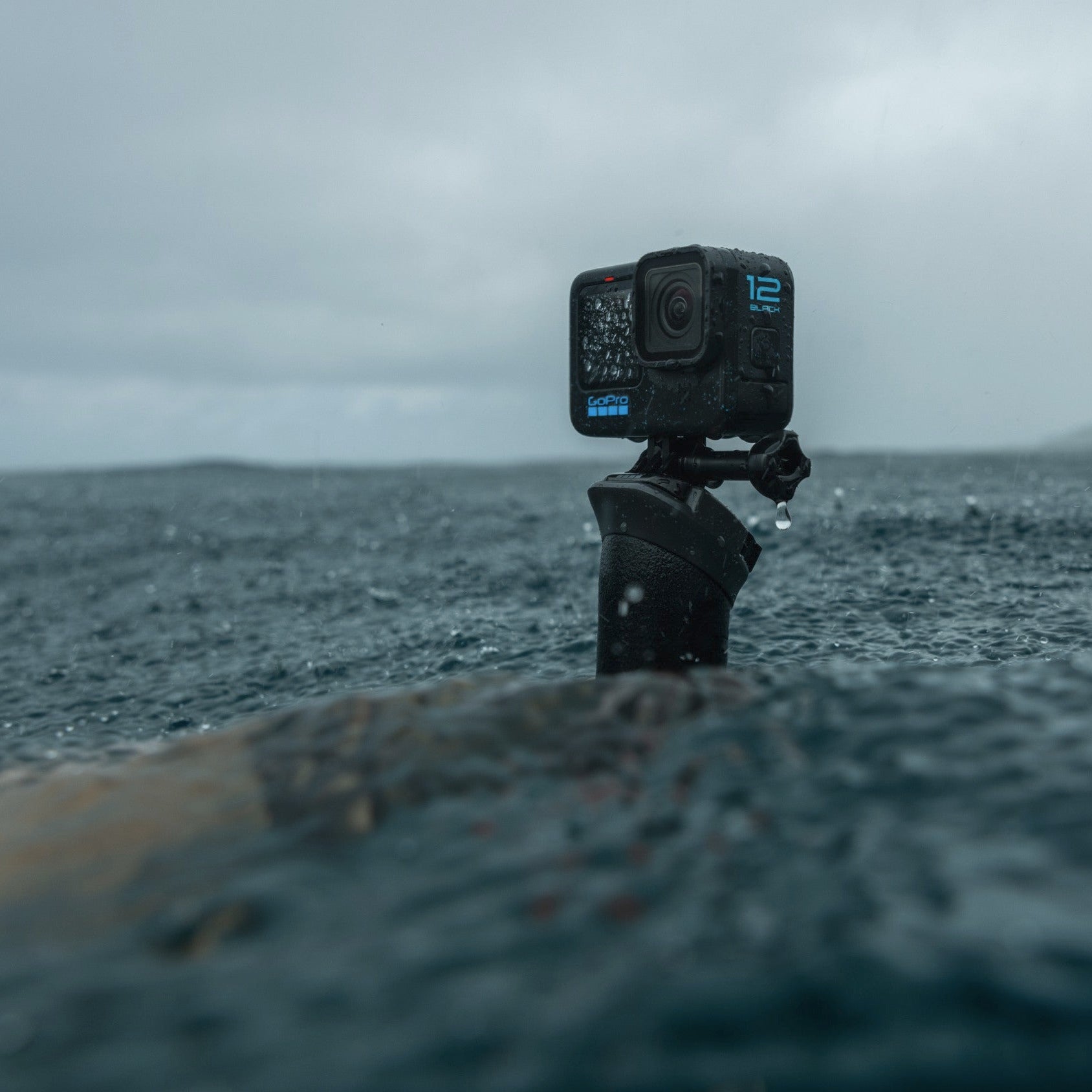 Action camera mounted on a surfboard with ocean and cloudy sky in the background