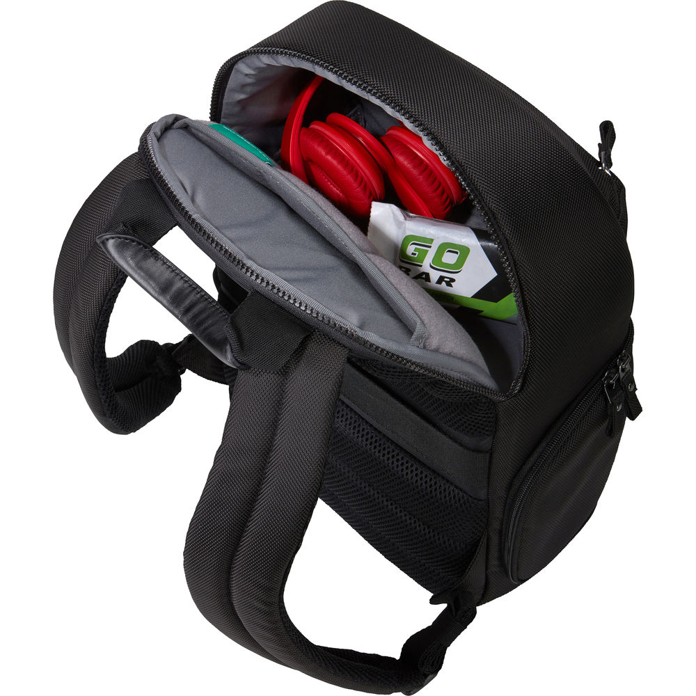 Black backpack with open front compartment showing red and green items on a white background