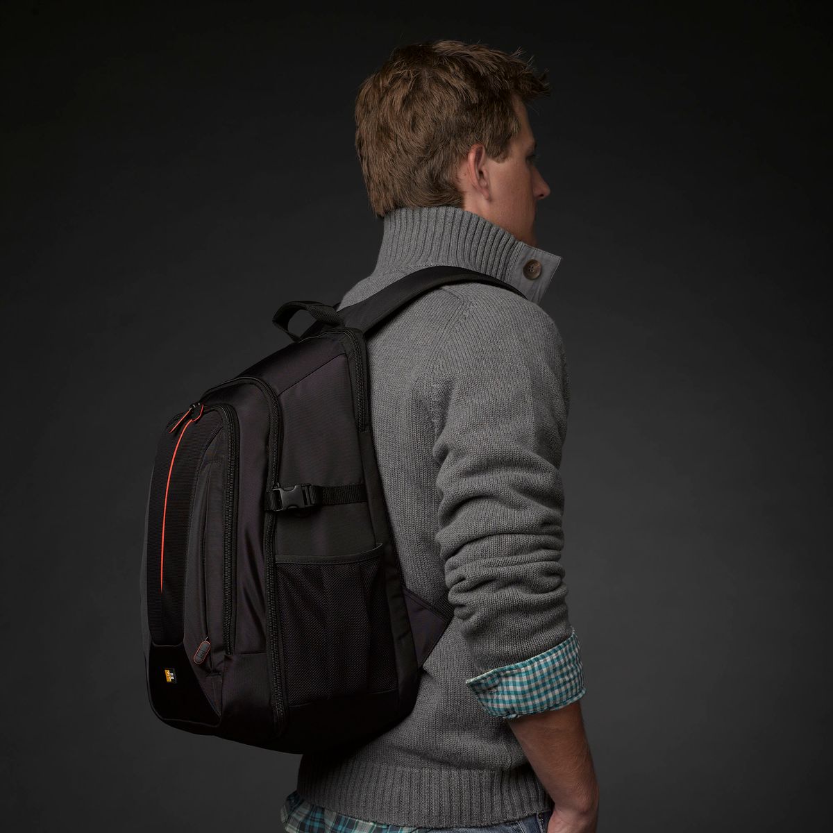 Man wearing a black backpack against a dark background