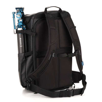 Black backpack with a camera tripod attached on a white background