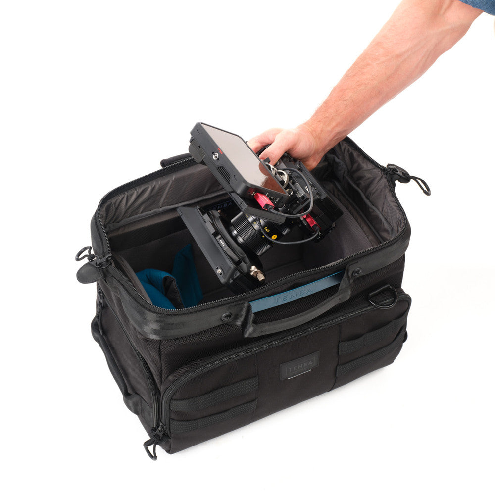 Black travel bag with a hand reaching in to adjust equipment on a white background
