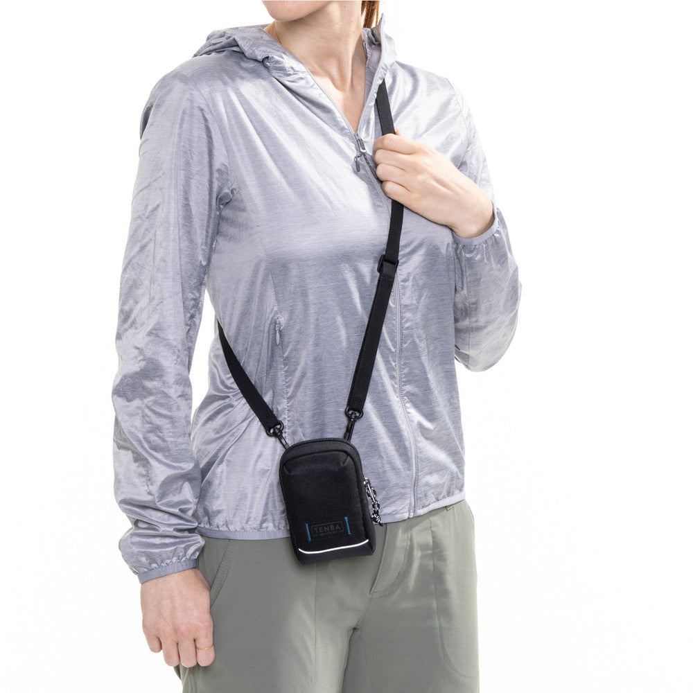 Person wearing a transparent raincoat with a black crossbody bag on a white background