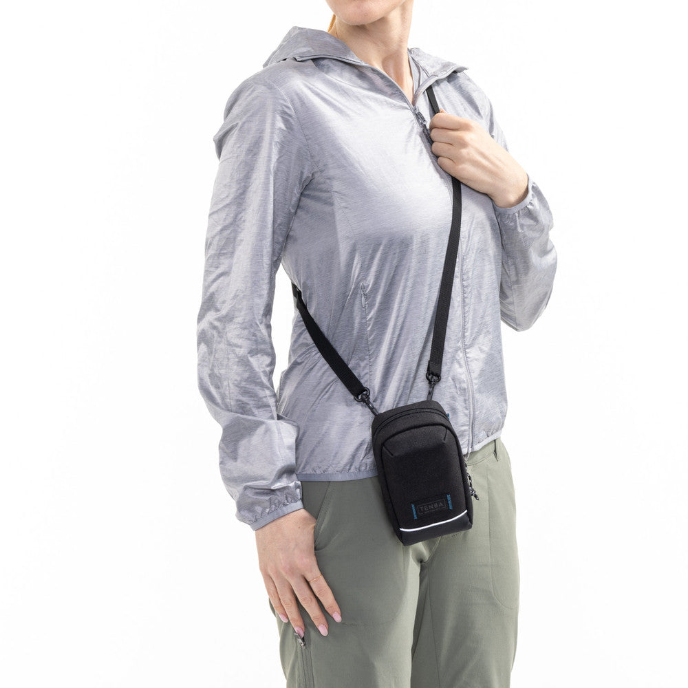 Person wearing a transparent raincoat with a black crossbody bag on a white background