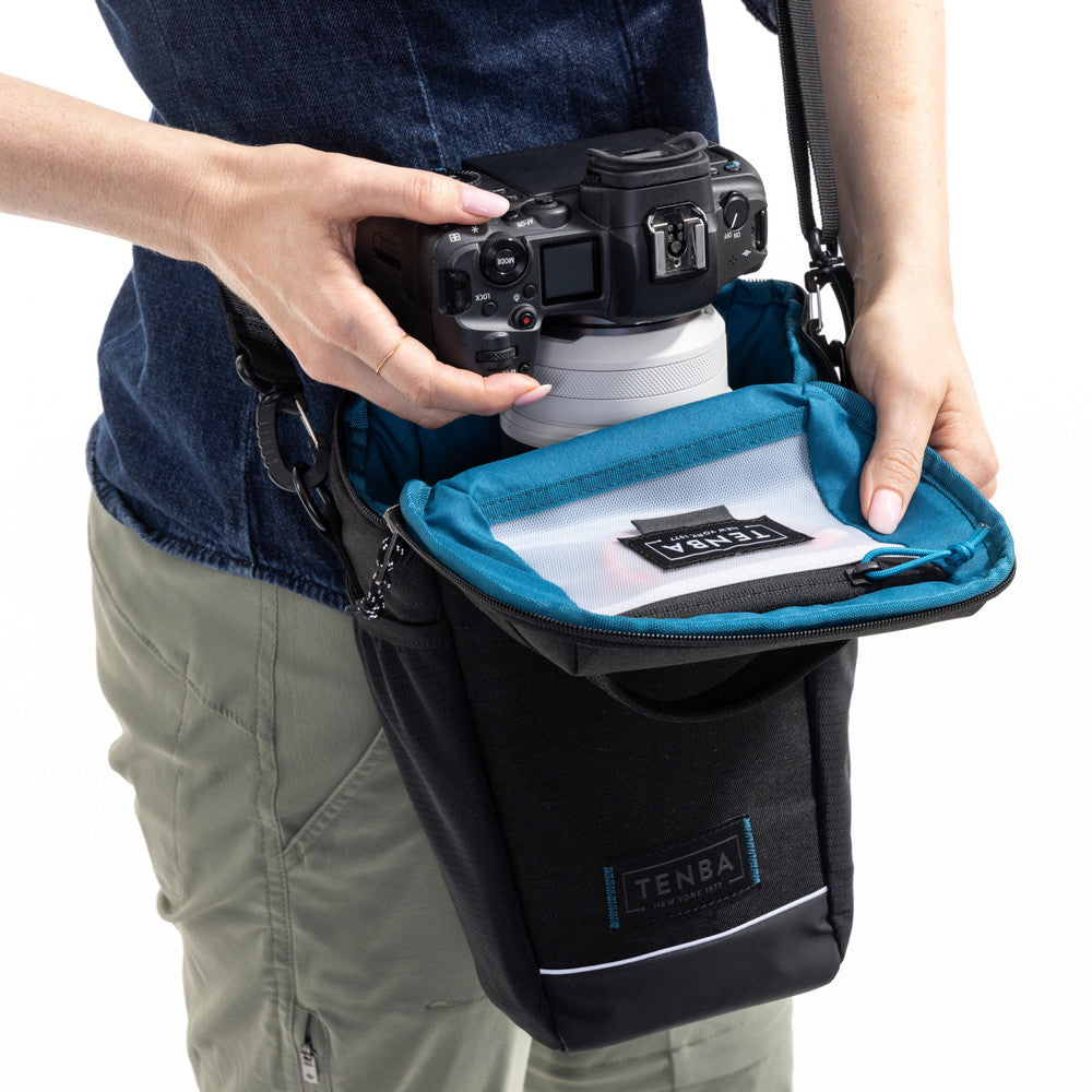 Person holding a camera with a Tenba bag on a white background