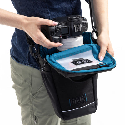 Person holding a camera with a Tenba bag on a white background