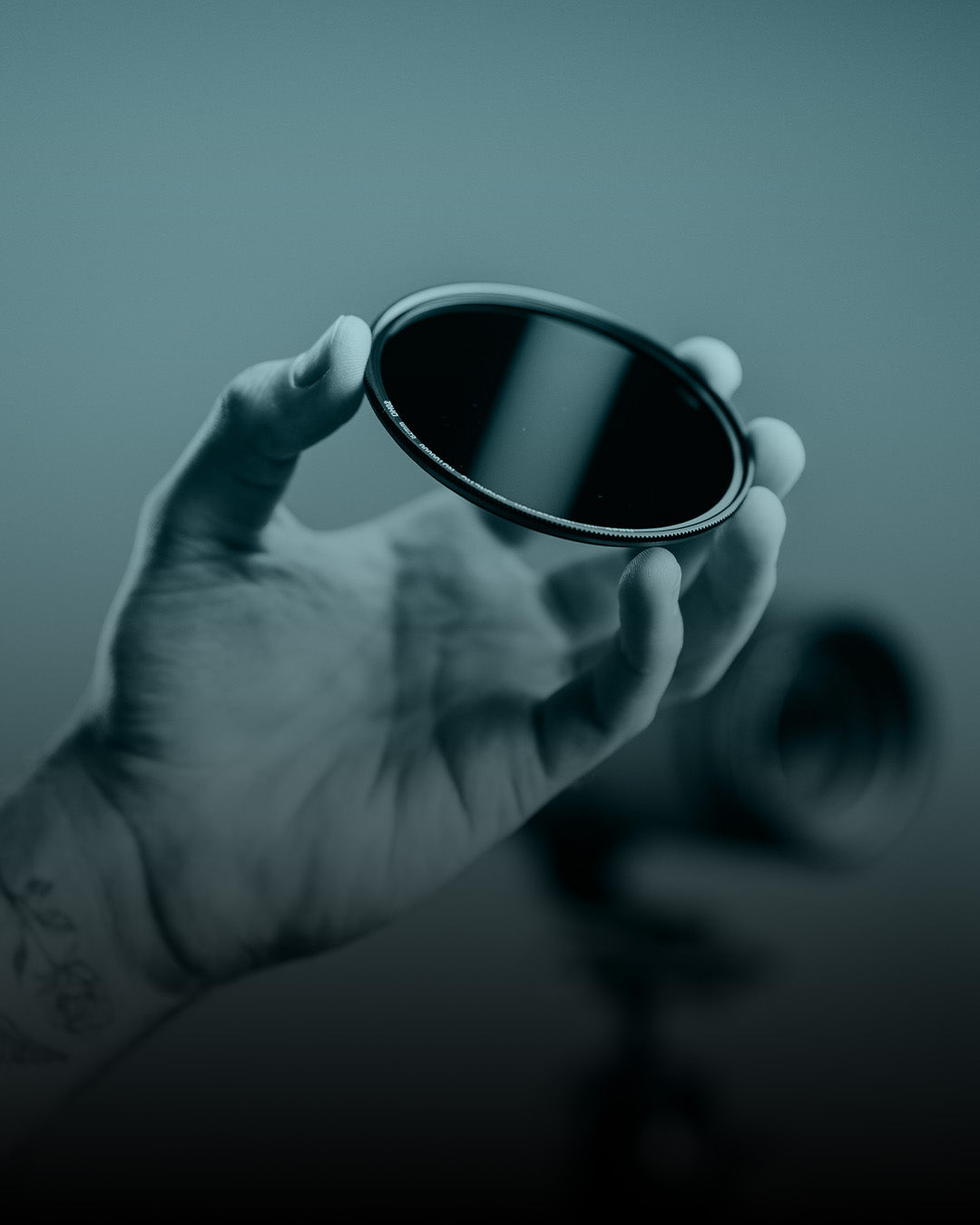 Hand holding a reflective object against a blurred background