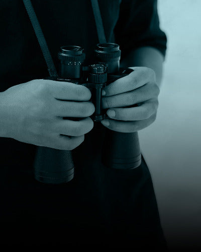 Person holding binoculars with a blurred background