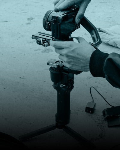Person adjusting a camera on a tripod with a blurred background