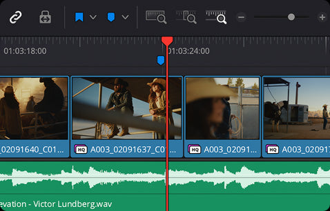 A screenshot of a video editing timeline interface with multiple clip thumbnails, a red playhead marker, and a green audio waveform track at the bottom.