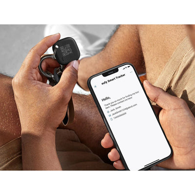 Person holding a keychain with a smart tracker and a smartphone displaying app interface.