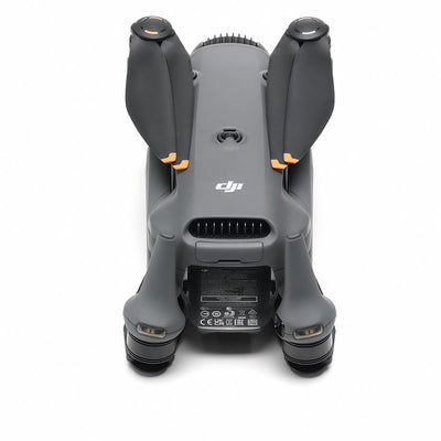 A grey DJI Mavic 4 Pro drone is shown from the front with its four arms extended and its triple-camera system visible
