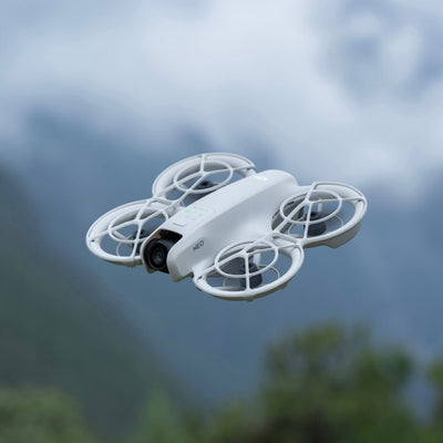 White drone flying against a blurred natural background