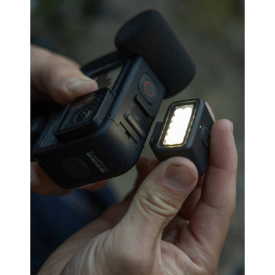 Hand holding a camera with a light attached, blurred background