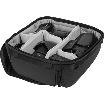 Black handheld Peak Design Camera Cube V2 with adjustable dividers, zipper closure, and durable nylon exterior, perfect for carrying camera gear safely.
