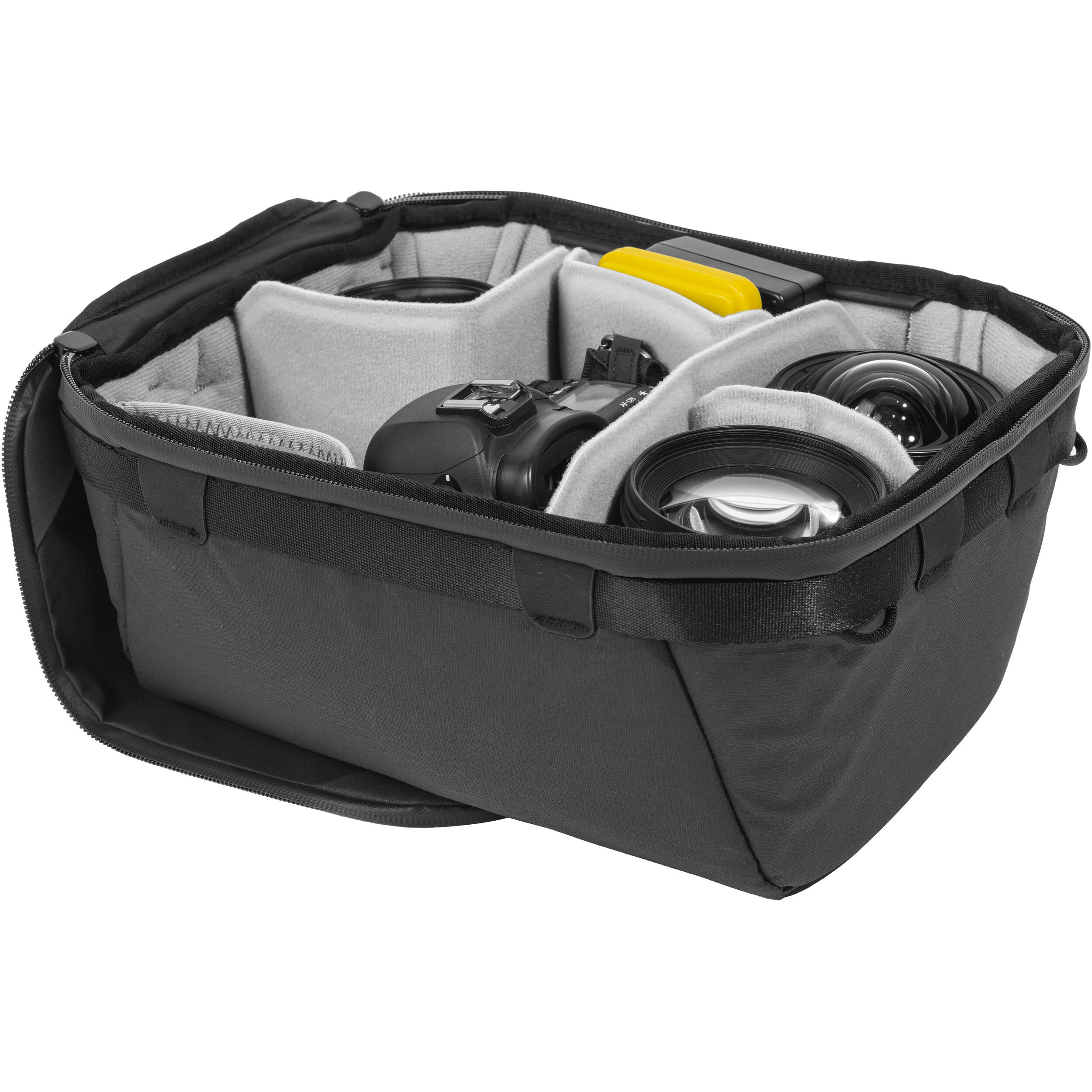 Black handheld Peak Design Camera Cube V2 with adjustable dividers, zipper closure, and durable nylon exterior, perfect for carrying camera gear safely.
