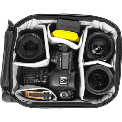 Black handheld Peak Design Camera Cube V2 with adjustable dividers, zipper closure, and durable nylon exterior, perfect for carrying camera gear safely.
