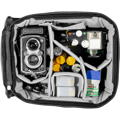 Black handheld Peak Design Camera Cube V2 with adjustable dividers, zipper closure, and durable nylon exterior, perfect for carrying camera gear safely.
