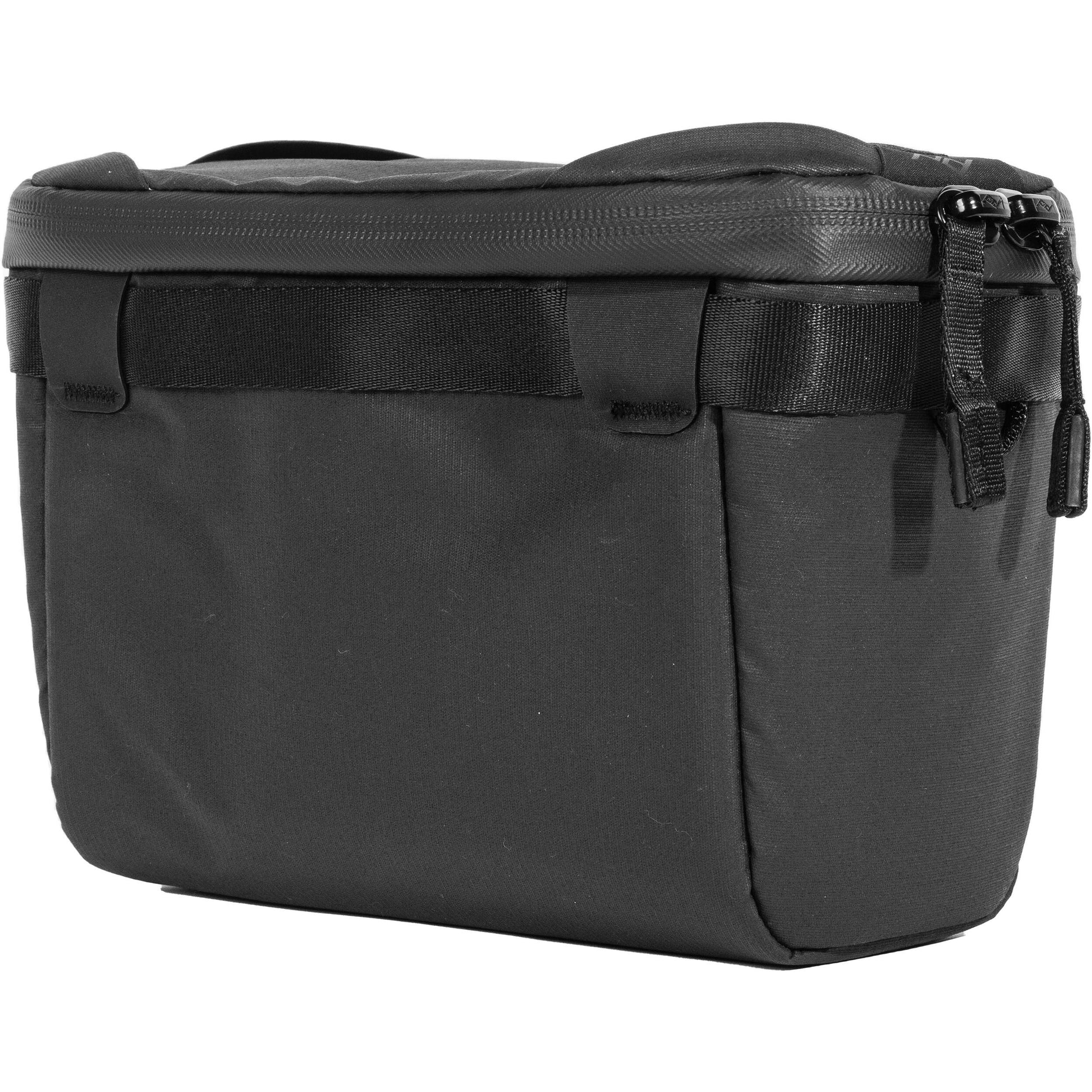 Black handheld Peak Design Camera Cube V2 with adjustable dividers, zipper closure, and durable nylon exterior, perfect for carrying camera gear safely.
