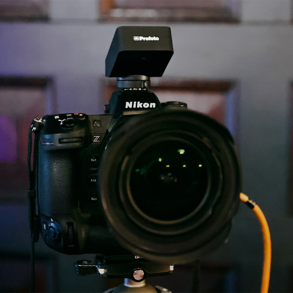 Nikon camera with a Profoto flash unit on a blurred indoor background