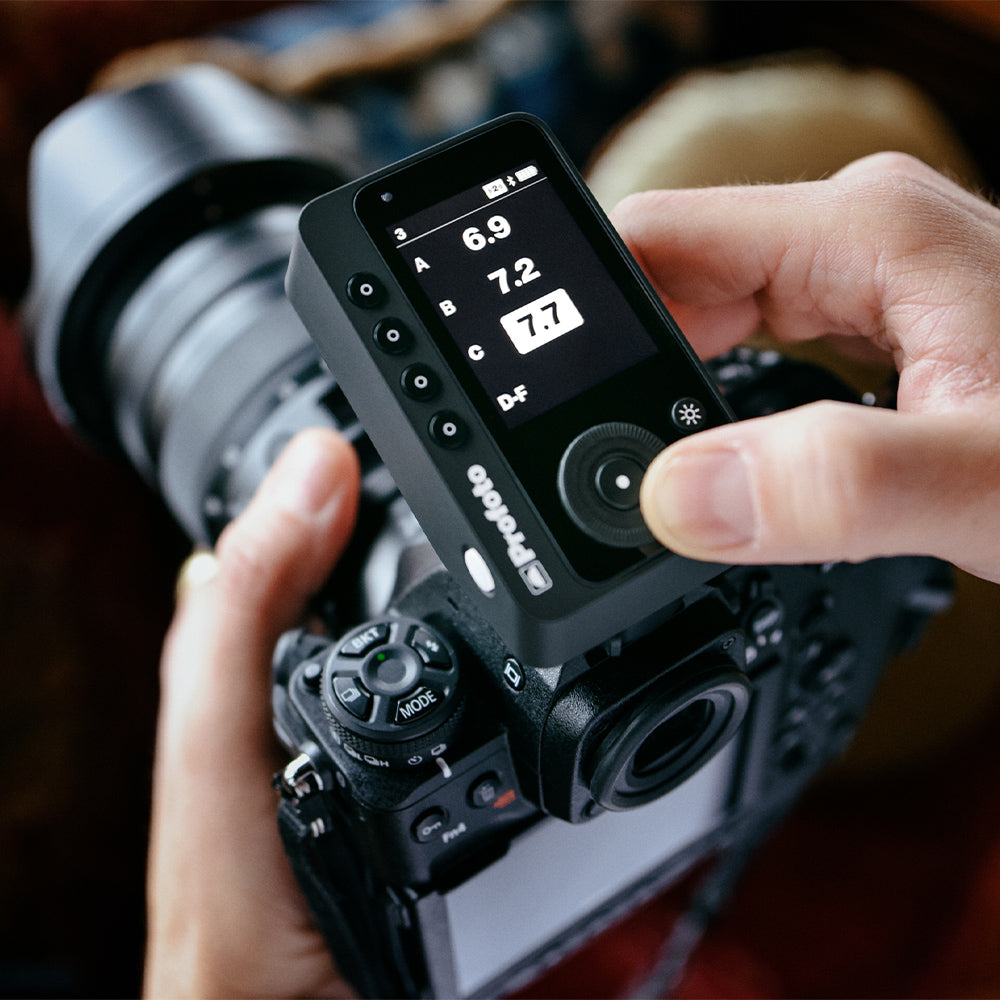 Person adjusting camera settings on a DSLR camera with a focus on the screen.