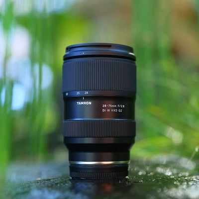 Camera lens on a grassy surface with a blurred natural background